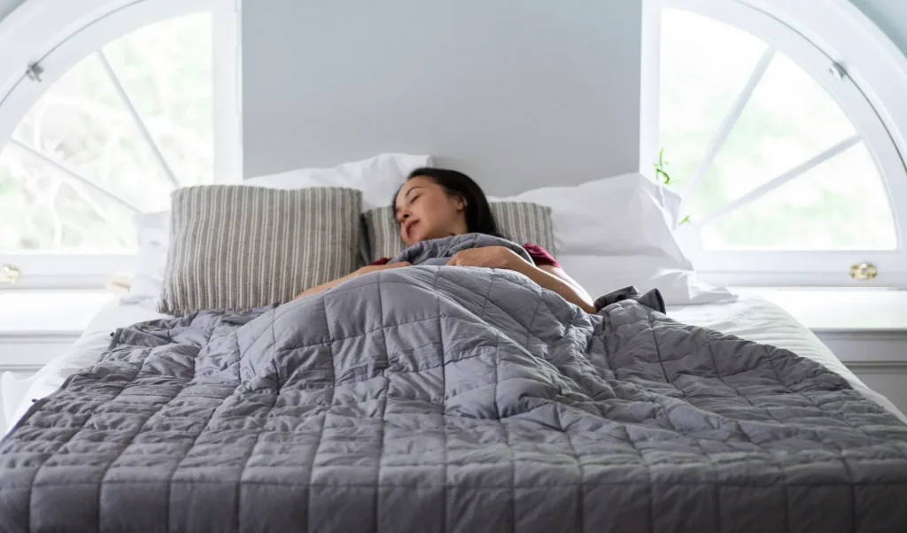 adult sleeping under a weighted blanket for anxiety relief